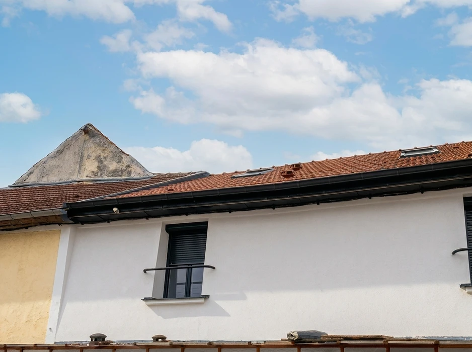 Vue extérieure de toiture en tuiles canal terre cuite, avec gouttière noire en PVC