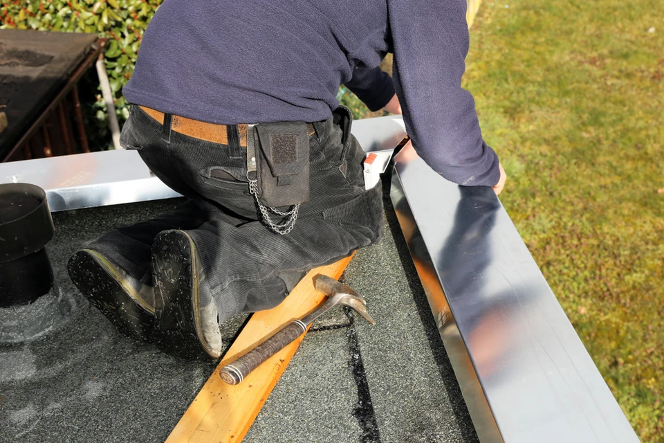 Couvreur professionnel travaillant sur une toiture, installant ou réparant des éléments de couverture