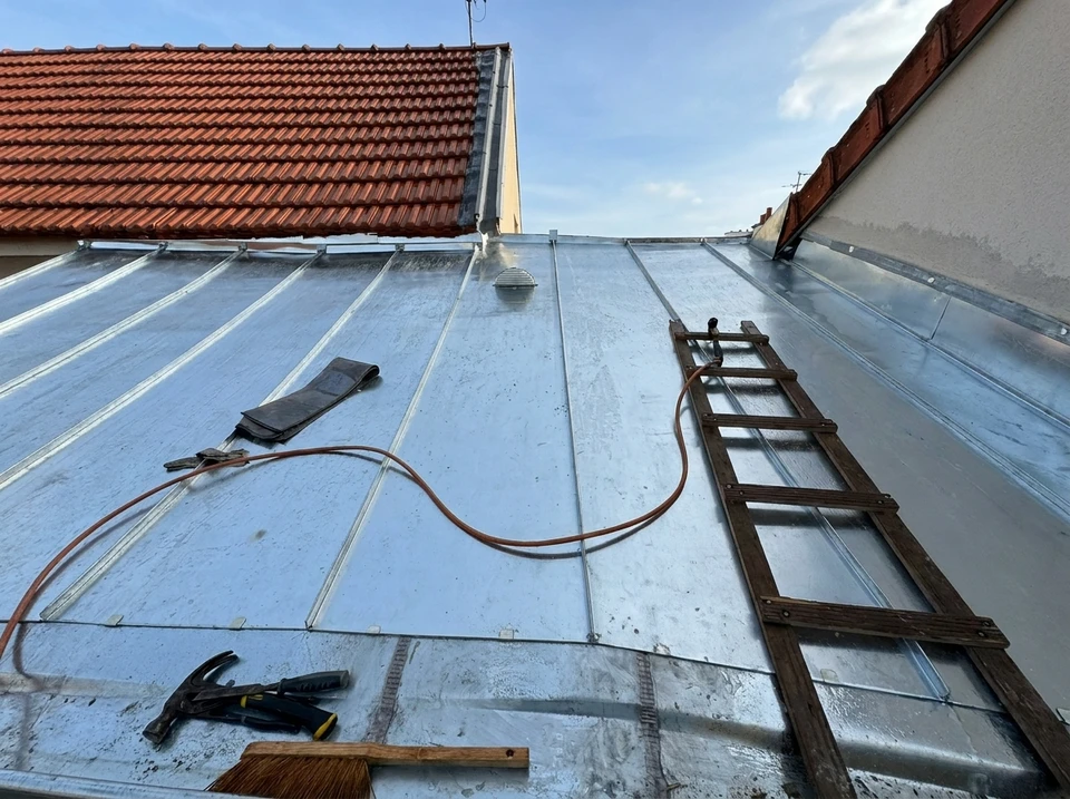 Chantier extérieur avec trois ouvriers équipés de harnais de sécurité rouge travaillant sur échafaudage métallique