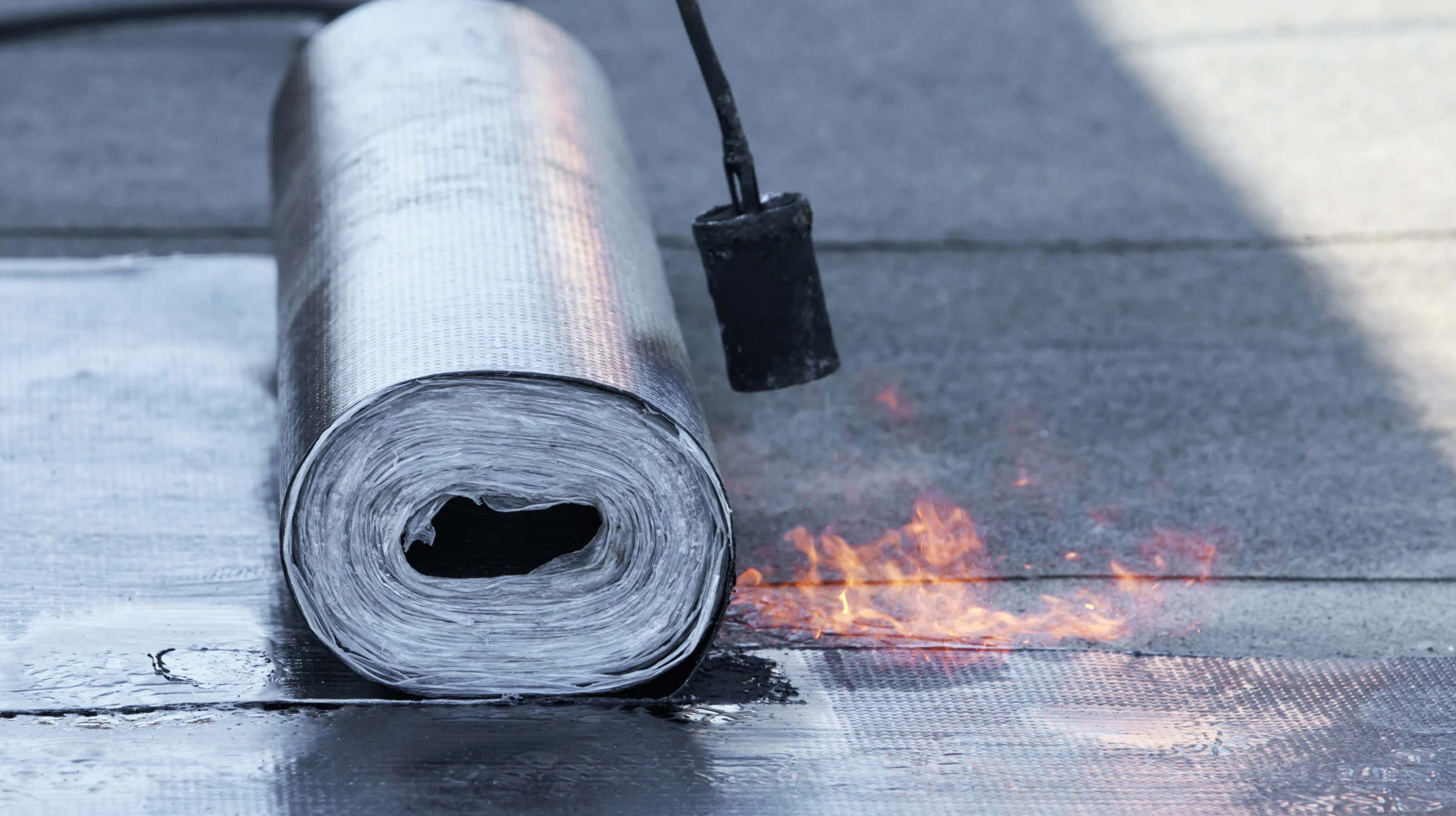 Chantier extérieur avec ouvrier en combinaison bleue installant une membrane d'étanchéité