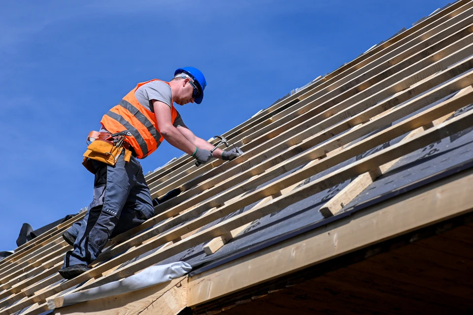 Chantier de construction intérieur avec deux hommes en casques de sécurité orange et rouge examinant des plans architecturaux